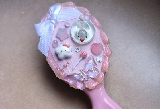 Pinceau rose décoré pour activité créative enfant avec ruban et mini accessoires ludiques et éducatifs.