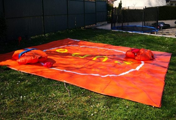Grande ouverte décorare tarp rouge sur pelouse avec accessoires gonflables orange, probablement prêt à être utilisé pour une