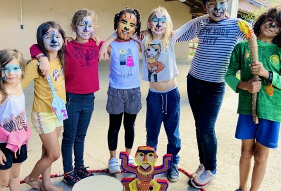 Groupe d’enfants et d’ados avec des maquillages colorés autour d’un jeu d’arcade en plein air, prêts à célébrer le thème anniversaire pour fille de 10 ans.