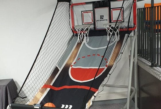 Terrain de basket-penteur intérieur avec filet de protection et ballon orange sur le bas de la rampe.
