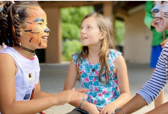 Trois enfants en activités d’anniversaire à Paris, visages peints comme des animaux, échangeant autour d’un atelier créatif. activit es anniversaire enfant paris